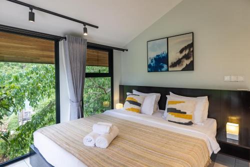 two beds in a bedroom with a large window at Payana Kampot in Kampot