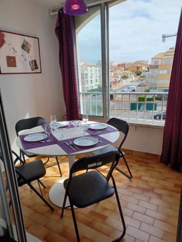 une table et des chaises dans une pièce avec une grande fenêtre dans l'établissement appartement avant port, au Cap d'Agde
