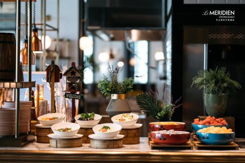 a table with bowls of food and plants on it at Le Meridien Zhongshan in Zhongshan