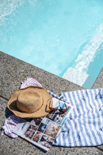 a hat and a magazine next to a swimming pool at Shelley Beach Retreat Kilcunda in Kilcunda