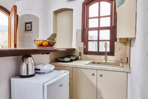 a kitchen with a sink and a refrigerator at Mila Malia Studios Hotel in Malia