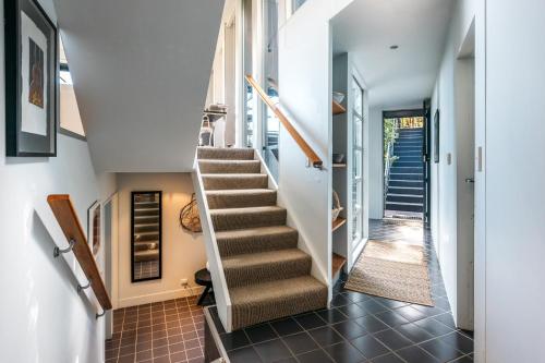 a staircase in a home with white walls and brown tile floors at Te Kereru, Onetangi in Waiheke Island