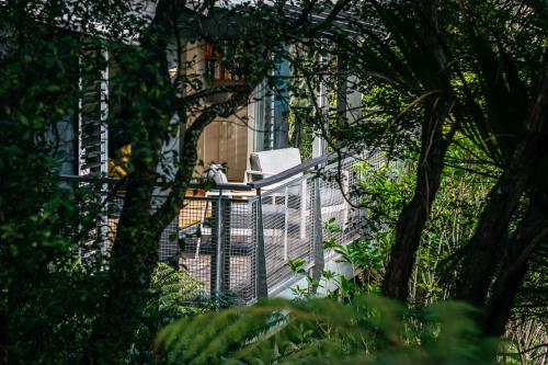 a cat sitting on a chair on a fence at Te Kereru, Onetangi in Waiheke Island