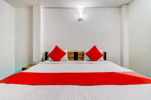 a bedroom with a white bed with red pillows at Hotel O Dhruv Inn in Izatnagar