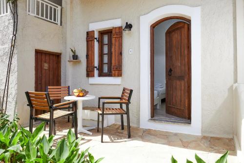 a patio with two chairs and a table and a door at Mila Malia Studios Hotel in Malia