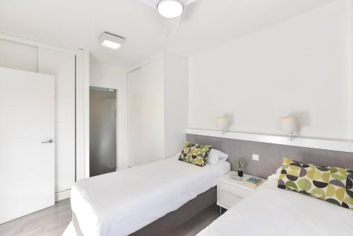 a white bedroom with two beds and a mirror at Modern Iguazu Apartment in Playa del Ingles