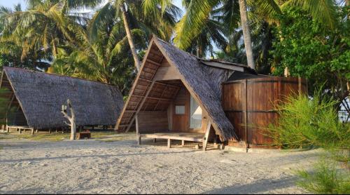 a small hut on the beach with palm trees at Kimo Resort Pulau Banyak Aceh Singkil in Alaban