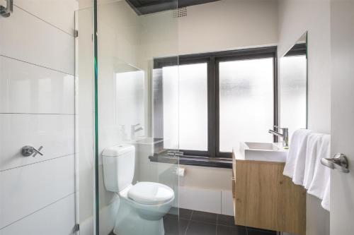 a bathroom with a toilet and a sink and a window at Nightcap at Chester Hill Hotel in Bankstown