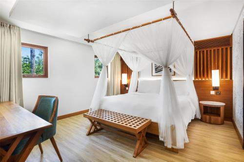 a bedroom with a canopy bed and a table at Kempinski Seychelles Resort in Baie Lazare Mahé