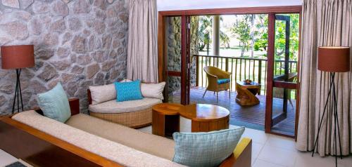 a living room with a couch and chairs on a balcony at Kempinski Seychelles Resort in Baie Lazare Mahé