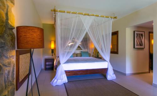 a bedroom with a canopy bed with mosquito nets at Kempinski Seychelles Resort in Baie Lazare Mahé