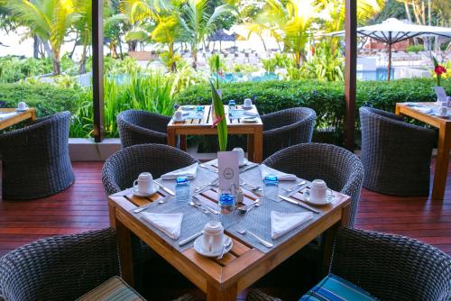 a table in a restaurant with chairs and a table with cups and plates at Kempinski Seychelles Resort in Baie Lazare Mahé