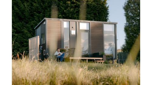 a woman sitting in front of a tiny house at Harrington's on the Terrace - Murchison by Tiny Away in Te Anau