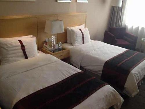 a hotel room with two beds and a chair at Ramada Plaza Shenyang Citycenter in Shenyang