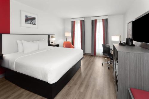 a hotel room with a bed and a desk and a tv at Ramada by Wyndham Milwaukee in Milwaukee