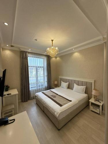 a bedroom with a large bed and a chandelier at HAYAT PLAZA HOTEL & Spa in Samarkand