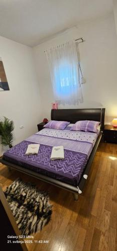 a bed in a bedroom with purple sheets and pillows at Adela Apartments - Beach Žnjan Split in Split