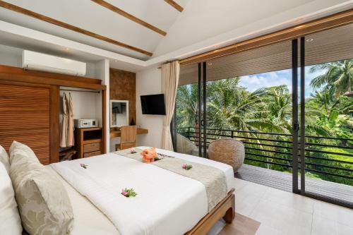 a bedroom with a bed and a large window at Khwan Beach Resort - Luxury Glamping and Pool Villas Samui - Adults Only - SHA Extra Plus in Mae Nam