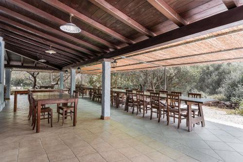 a covered patio with wooden tables and chairs at Su Birde Agriturismo in Orosei