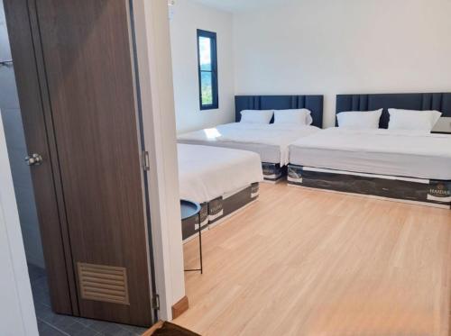 a room with two beds and a door to a bedroom at S HOUSE POOLVILLA Khaoyai in Pak Chong