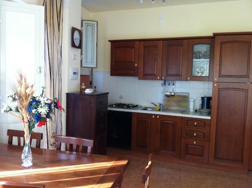 a kitchen with wooden cabinets and a table with a vase of flowers at Da Cristina Con Amore in Taormina