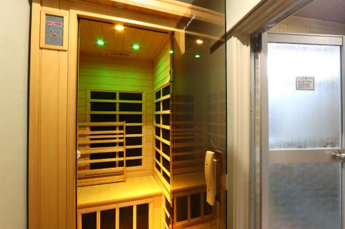 a small shower in a bathroom with green walls at Kenrokuen in Nobeoka
