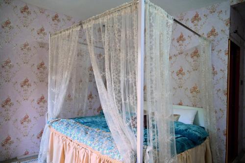 a bedroom with a canopy bed with white curtains at The Rare Ones, Bhalugaad Resort and game Zone in Mukteswar