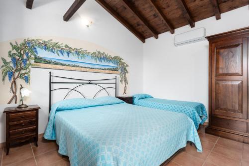 a bedroom with two beds with blue comforter at Su Birde Agriturismo in Orosei