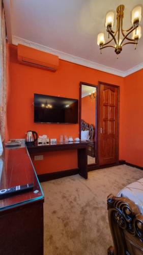 a bedroom with an orange wall with a desk and a mirror at Grandview Boutique Hotel in Baku