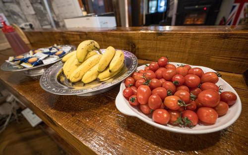 two plates of fruit on a counter with bananas and tomatoes at Daegu February Hotel Hwanggeum in Daegu