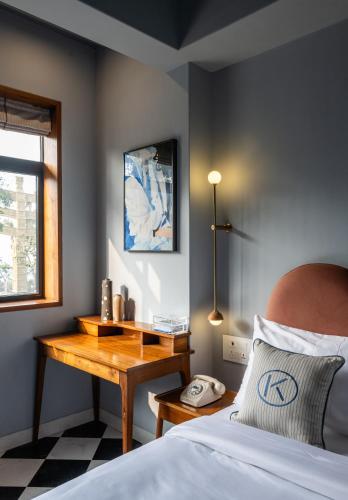 a bedroom with a bed with a wooden table and a telephone at The Kin Hotel in Mumbai