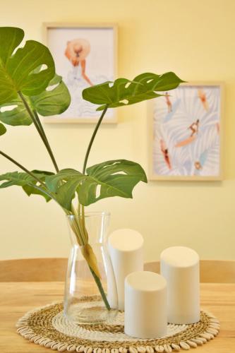 a vase with a plant and three white candles at Li Kotohogi 201 in Naha