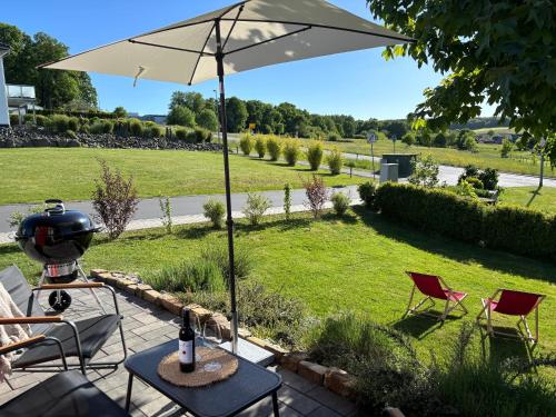 eine Terrasse mit Tisch, Sonnenschirm und Stühlen in der Unterkunft Auszeit im Tiny House LORE Westerwald in Steinebach