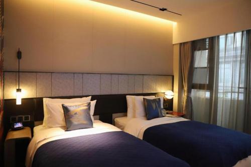 a hotel room with two beds and a window at Ethos Hotel Wuhan Riverside in Wuhan