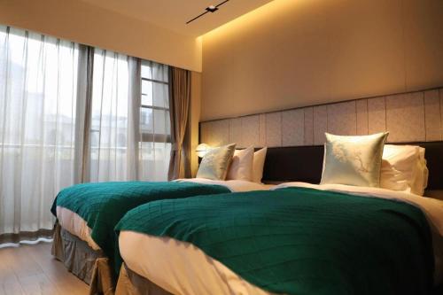 a bedroom with two beds with green and white sheets at Ethos Hotel Wuhan Riverside in Wuhan