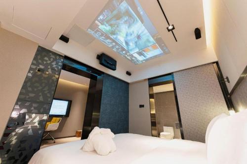 a bedroom with a white bed with a skylight at Ethos Hotel Wuhan Riverside in Wuhan