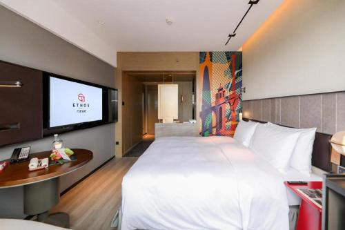 a hotel room with a large bed and a flat screen tv at Ethos Hotel Wuhan Riverside in Wuhan