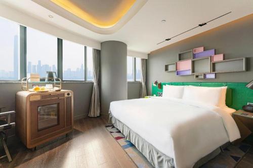 a hotel room with a large bed and a television at Ethos Hotel Wuhan Riverside in Wuhan