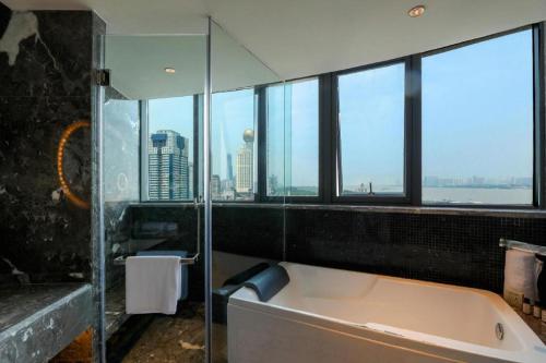 a bathroom with a tub with a view of the city at Ethos Hotel Wuhan Riverside in Wuhan