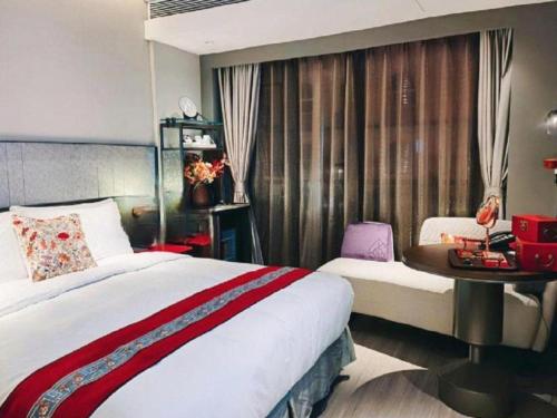 a bedroom with a bed and a table and a window at Ethos Hotel Wuhan Riverside in Wuhan