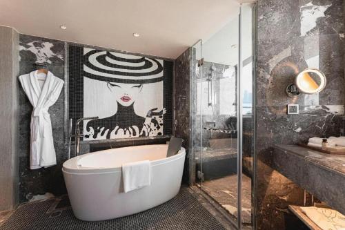 a bathroom with a tub and a painting of a woman at Ethos Hotel Wuhan Riverside in Wuhan