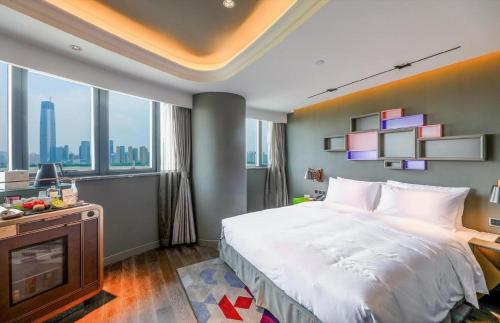 a bedroom with a large bed and a television at Ethos Hotel Wuhan Riverside in Wuhan