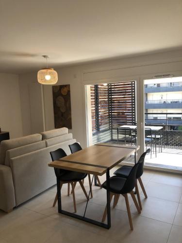 un salon avec une table, des chaises et un canapé dans l'établissement Appartement T2 46 m2 O'Lac proche du lac 1 chambre parking terrasse, à Aix-les-Bains