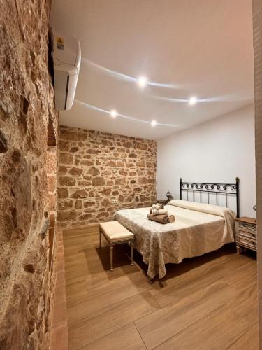 sypialnia z łóżkiem i kamienną ścianą w obiekcie La casa del castillo w mieście Baños de la Encina