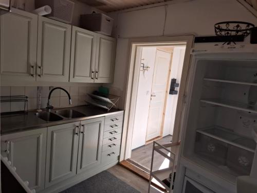 a kitchen with white cabinets and a sink and a door at Ferienhaus am See (Rådasjön) in Råda
