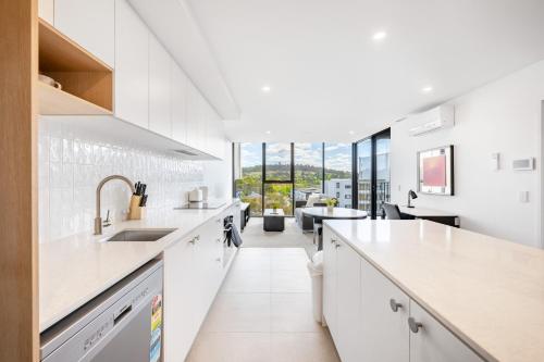 a kitchen with white countertops and a living room at Self-Contained Apartment in Woden By Serain in Phillip
