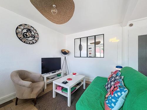 - un salon avec un canapé vert et une télévision dans l'établissement Maison colorée - 2 chambres - À 5 min de la mer, à Plérin