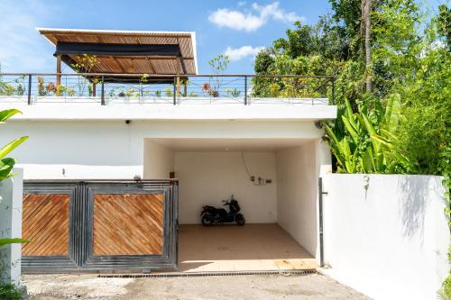 a house with a garage with a motorcycle parked in it at Villa Primarosa - Charming 3BR Villa with rooftop in Munggu