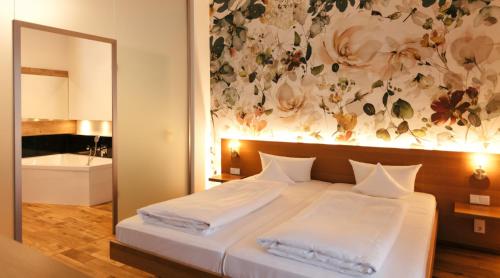 a bedroom with a large bed with a floral wall at B&O Parkhotel in Bad Aibling