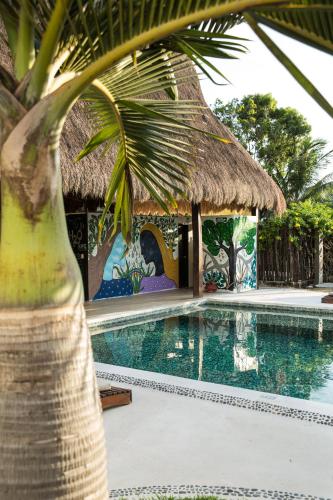 a villa with a swimming pool and a thatch hut at Villas H2O in Tulum